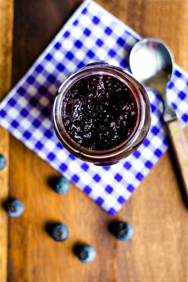 look down inside a jar of blueberry jam with blueberries scattered on the table
