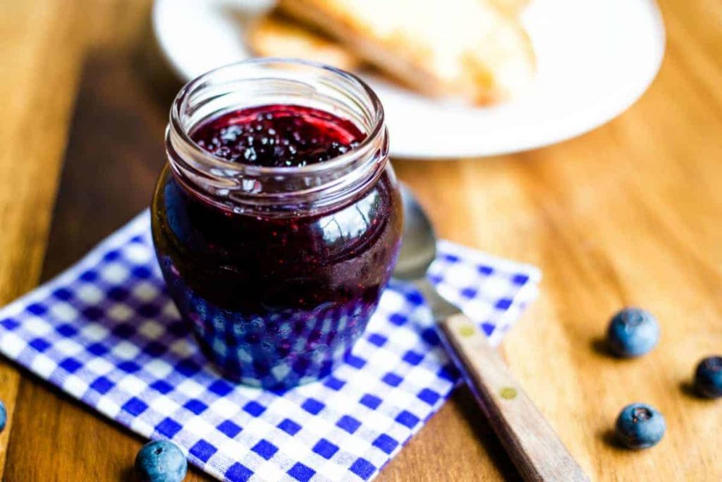 a jar of blueberry jam on a checked napkin