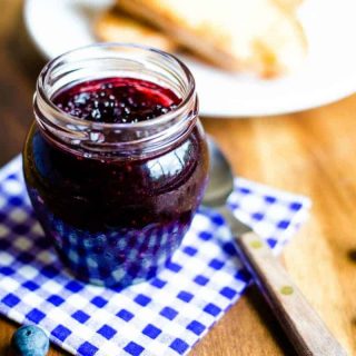 a jar of blueberry jam on a checked napkin