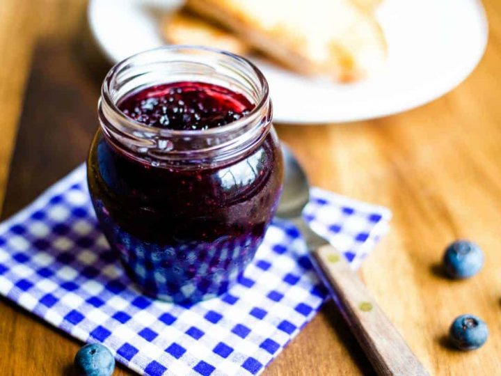 a jar of blueberry jam on a checked napkin