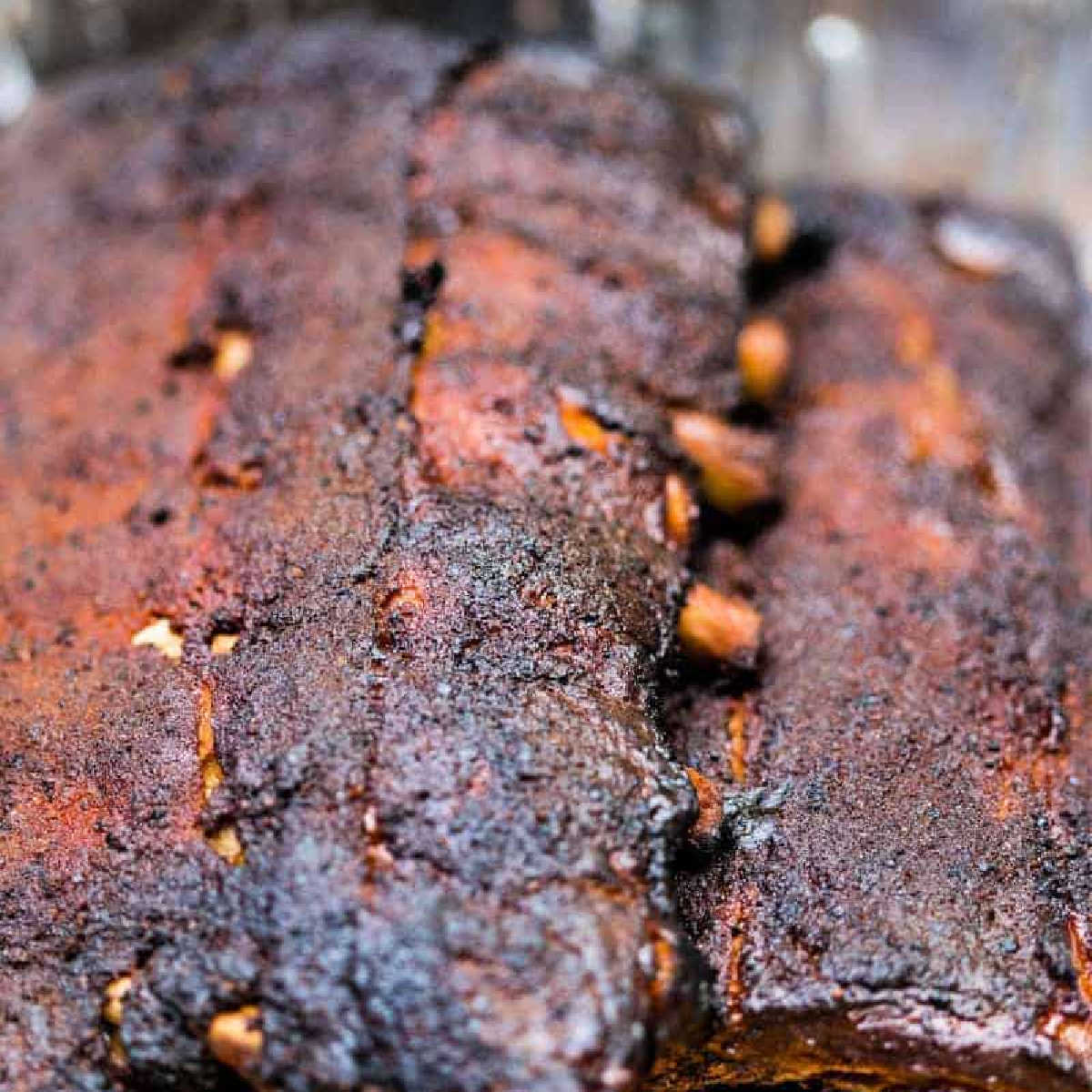 two racks of smoked baby back ribs in an aluminum pan.