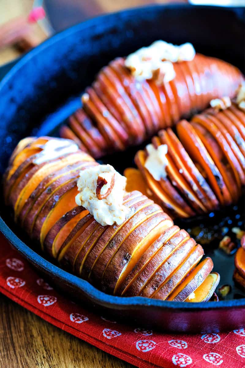 a slice sweet potato in an iron skillet with butter and pecans