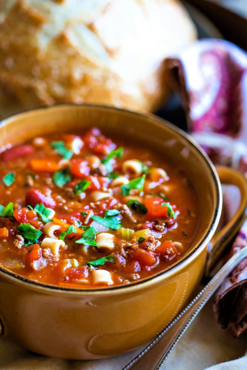 A bowl of Pasta e Fagioli Soup with tomatoes and beans garnished with parsley