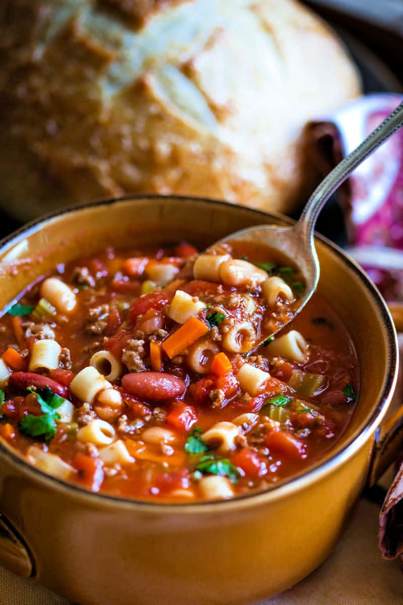 lifting a spoonful of Pasta e Fagioli Soup out of a bowl of soup