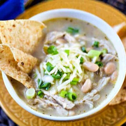 A bowl of food on a plate, with white chicken chili
