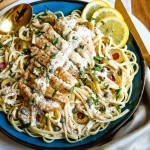 lemon chicken over pasta on a blue plate with lemon slices