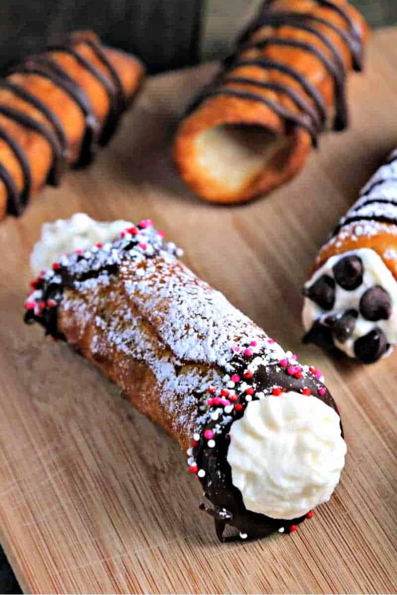 filled cannoli dusted with powdered sugar and dipped in chocolate