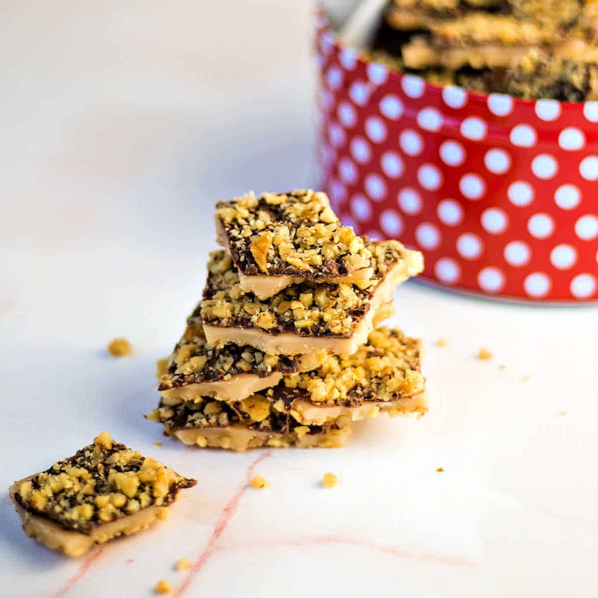 a stack of English toffee on a table with an open tin of more toffee