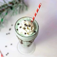 top down view of mint chocolate chip milkshake in a soda glass with a red striped straw