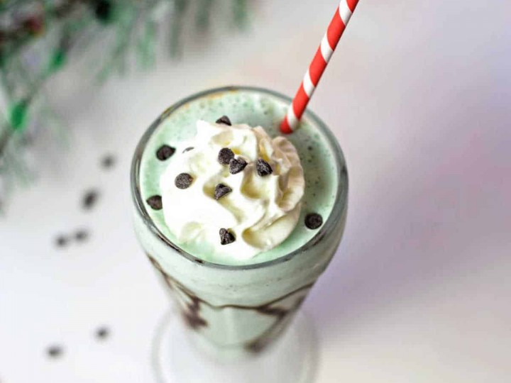 top down view of mint chocolate chip milkshake in a soda glass with a red striped straw