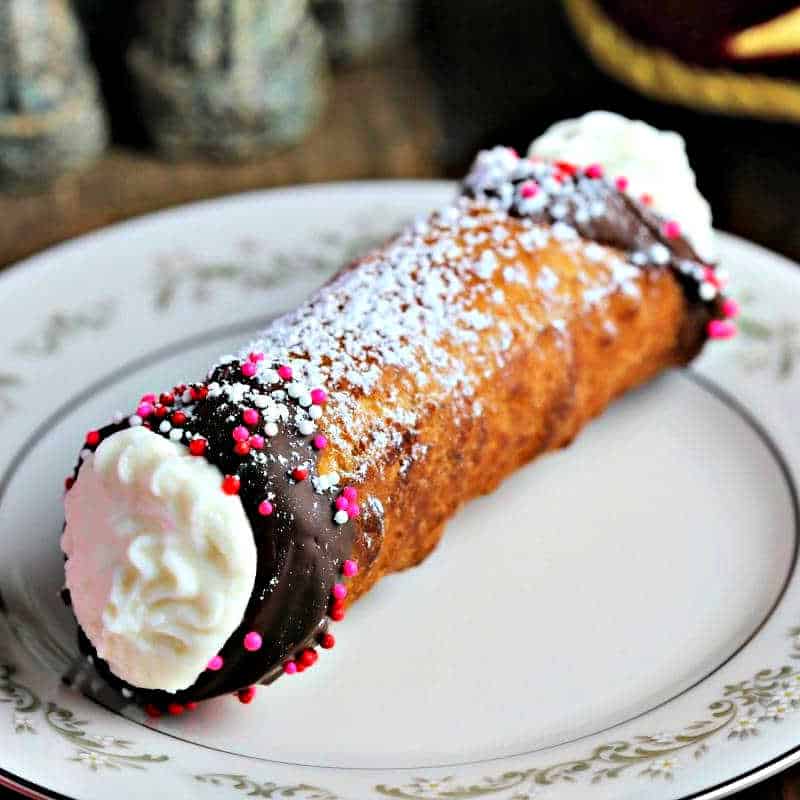 a homemade cannoli dipped in chocolate on a china plate