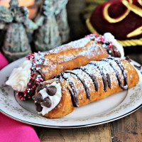 two cannolis on a china plate