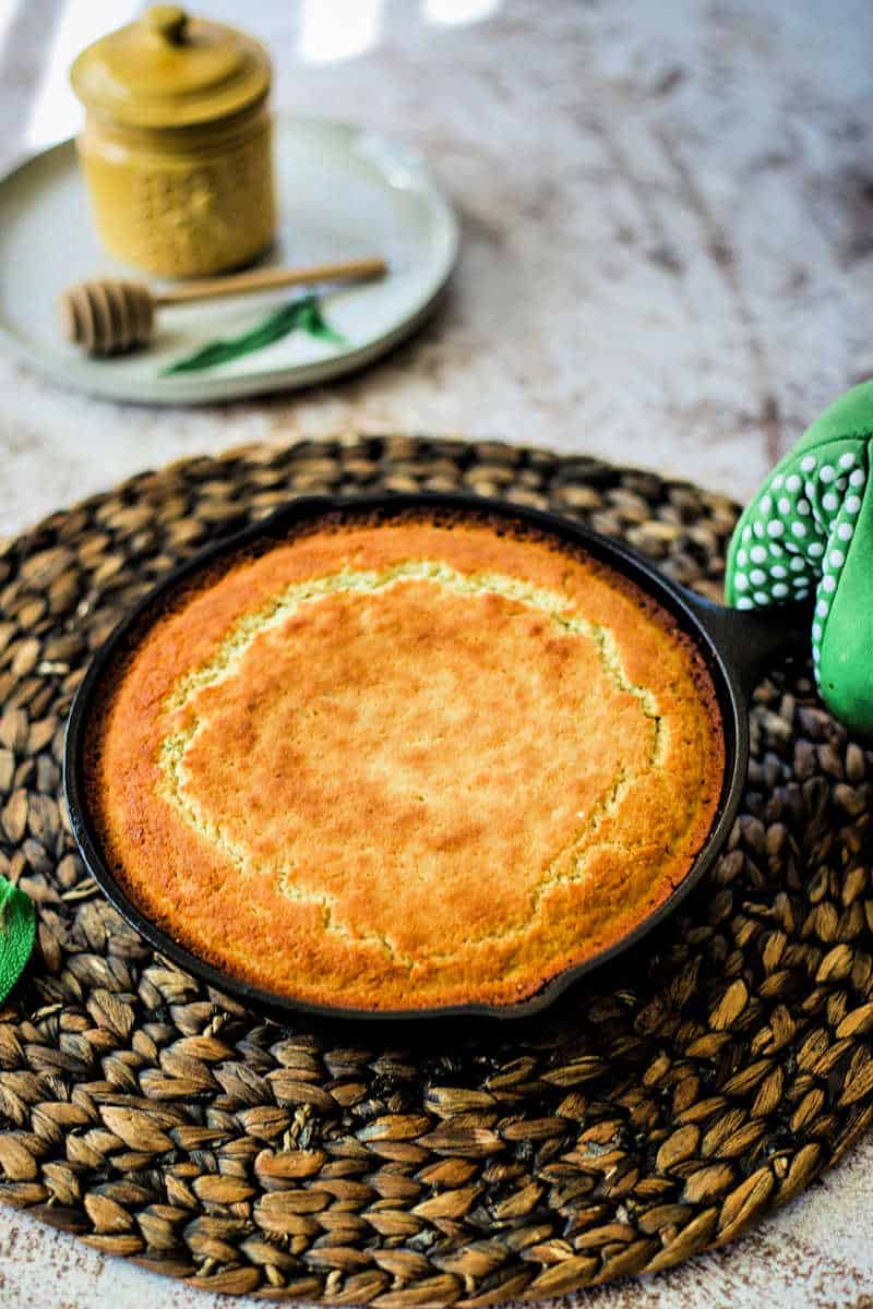 Honey Cornbread with Sage in a cast iron skillet on a heat pad