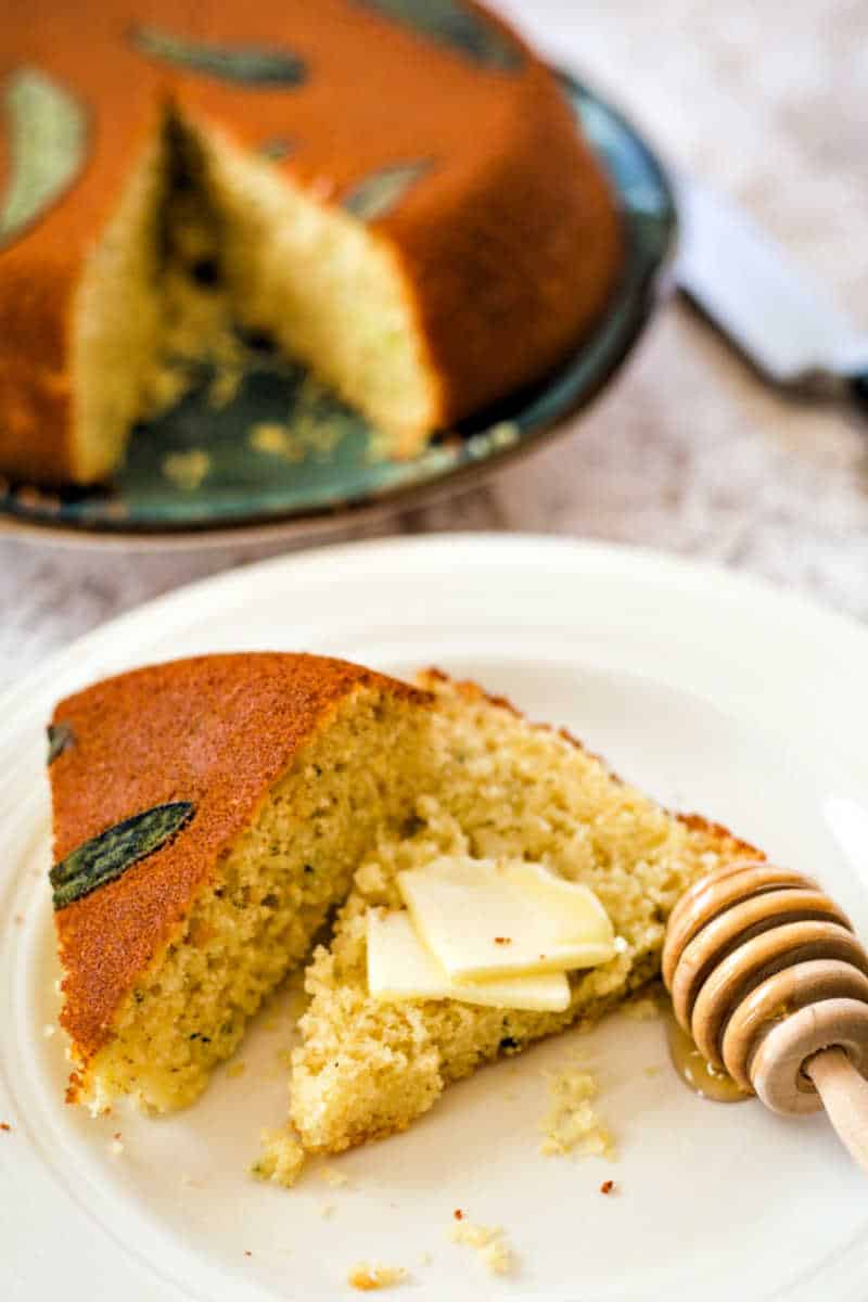 Honey Cornbread with Sage sliced open on a white plate with a honey spoon