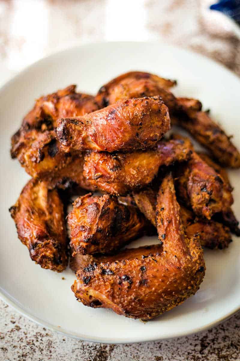 a pile of smoked chicken wings on a white plate