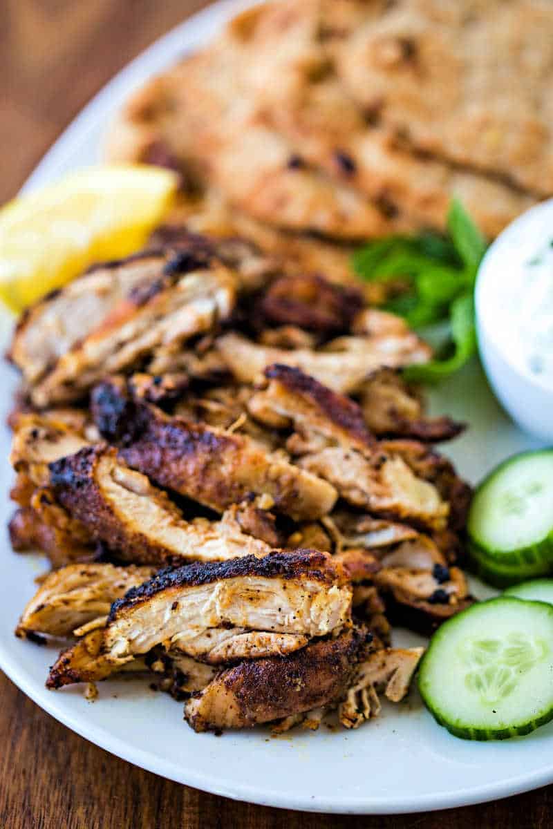 chicken shawarma on white platter with naan and cucumber slices