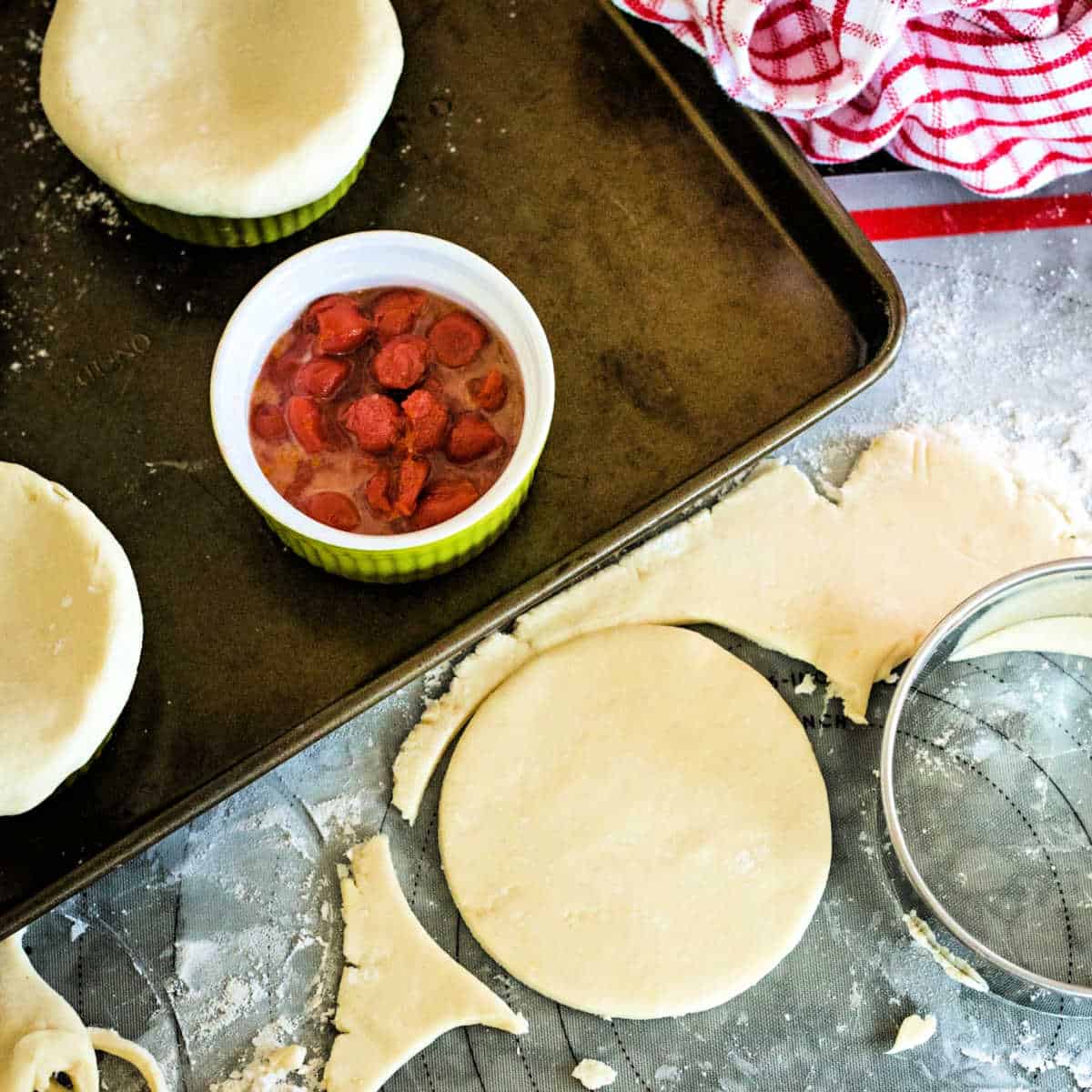 fitting pie dough on top of cherry pot pies