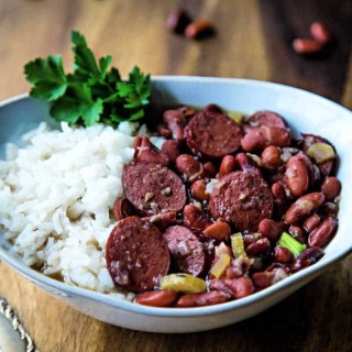 red beans and rice in a white bowl with a fork on a wooden table