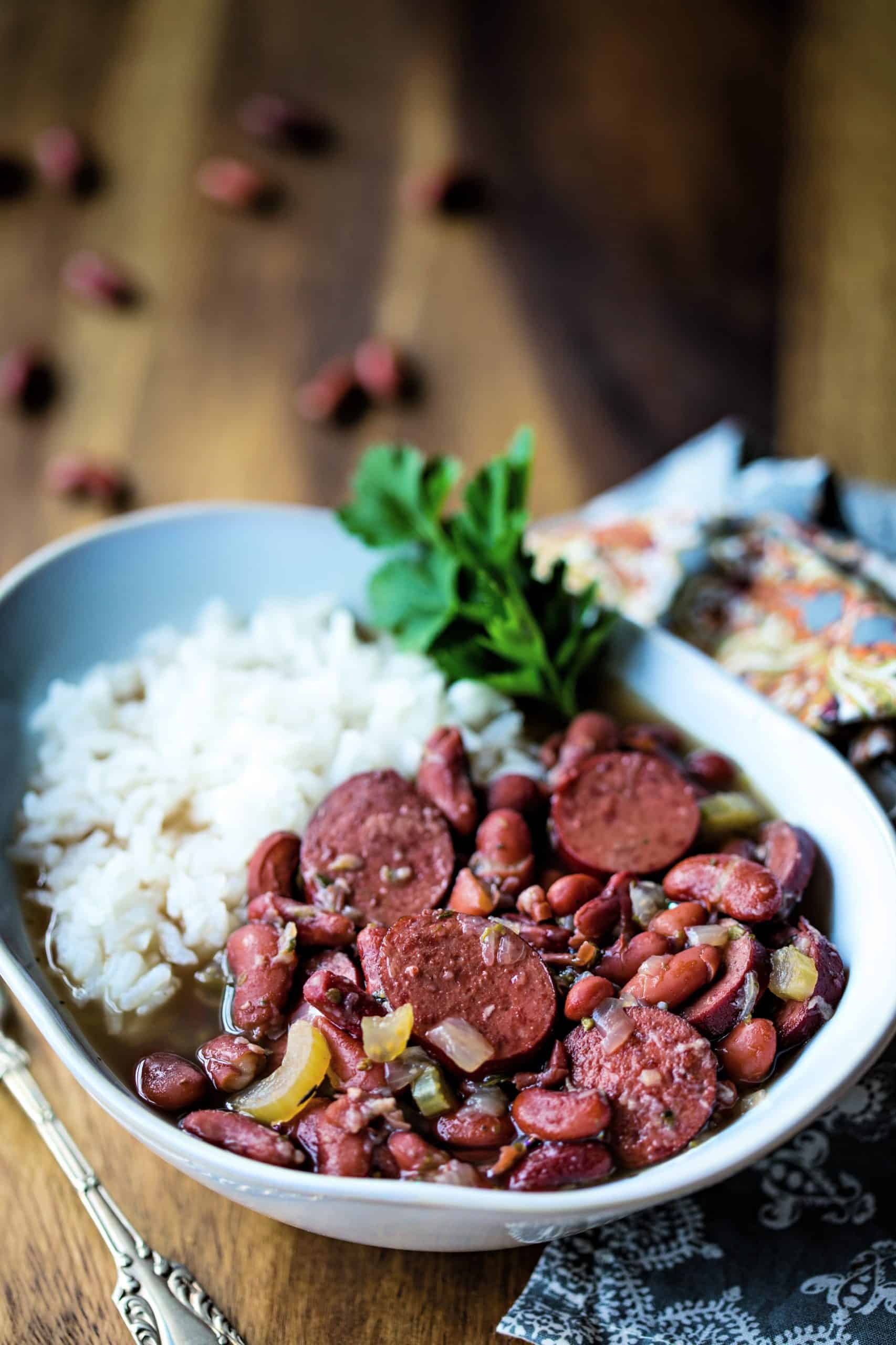 red beans and rice garnished with parsley in a white bowl with a fork on a wooden table