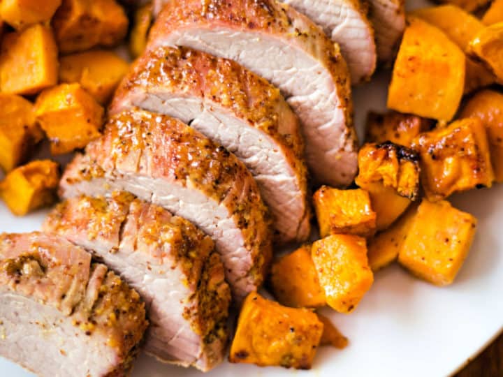 sliced Maple Dijon Oven-Roasted Pork Tenderloin with sweet potatoes on a white platter