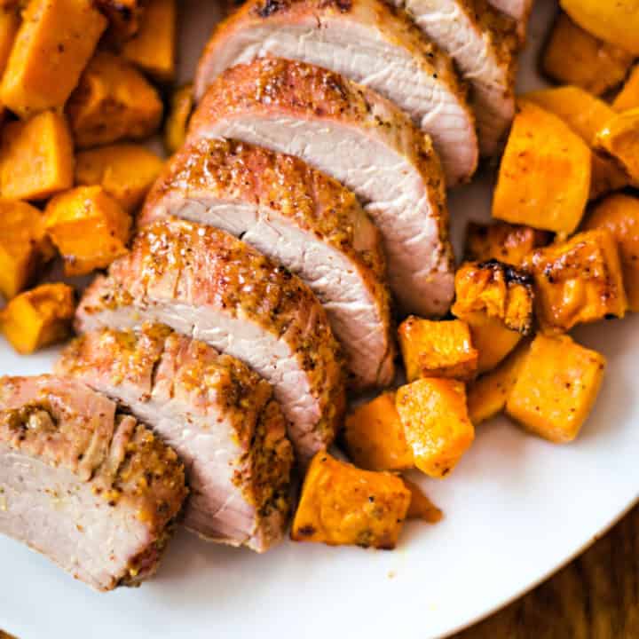 sliced Maple Dijon Oven-Roasted Pork Tenderloin with sweet potatoes on a white platter