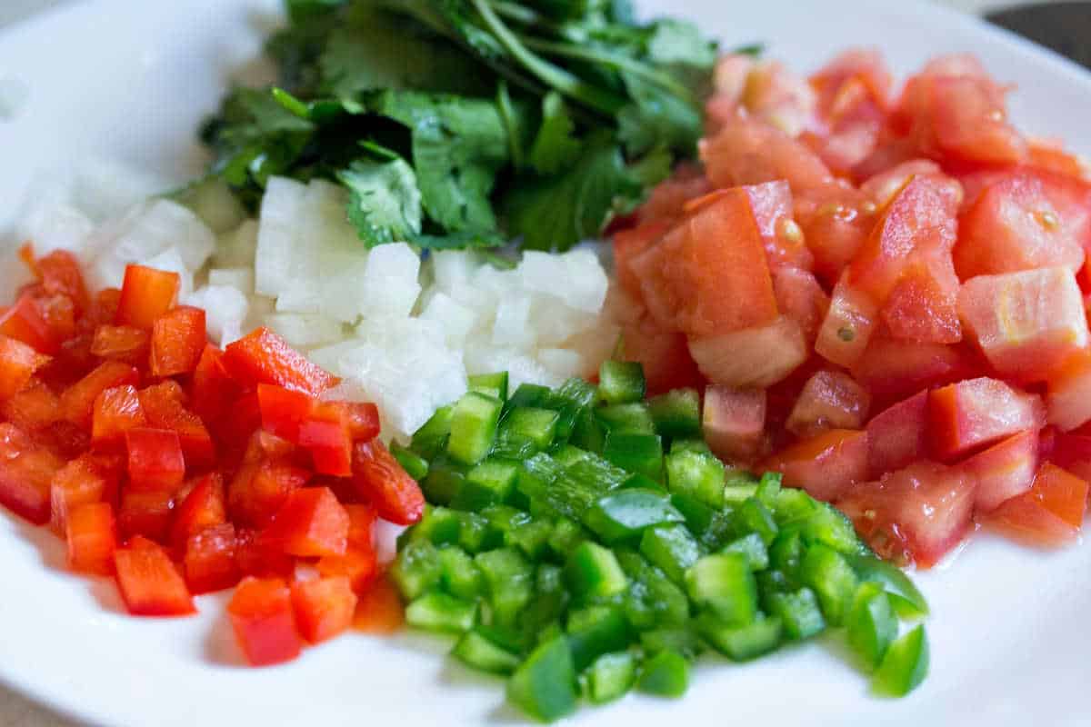 a plate of diced peppers, onions, tomatoes, and cilantro