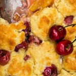 close up of a peach cherry cobbler with a serving spoon,