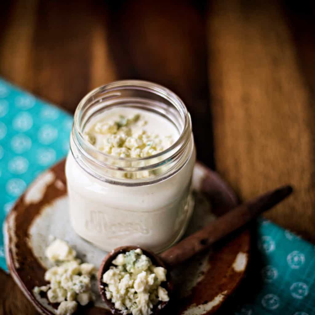 homemade buttermilk blue cheese dressing in a mason jar with blue cheese crumbles