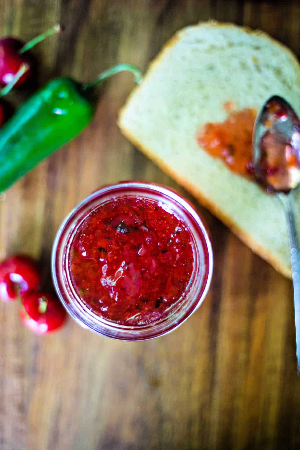 a spoon of hot cherry pepper jelly on a slice of bread