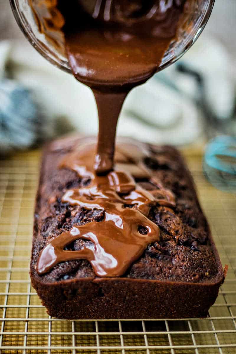 pouring glaze on top of chocolate cherry loaf cake