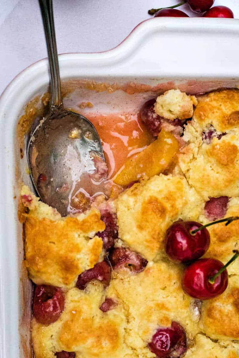 peach cherry cobbler in a baking dish with a spoon