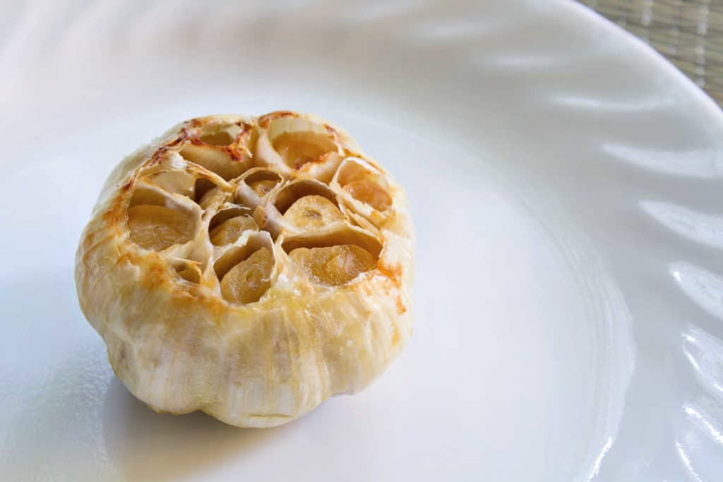 a head of roasted garlic on a white plate