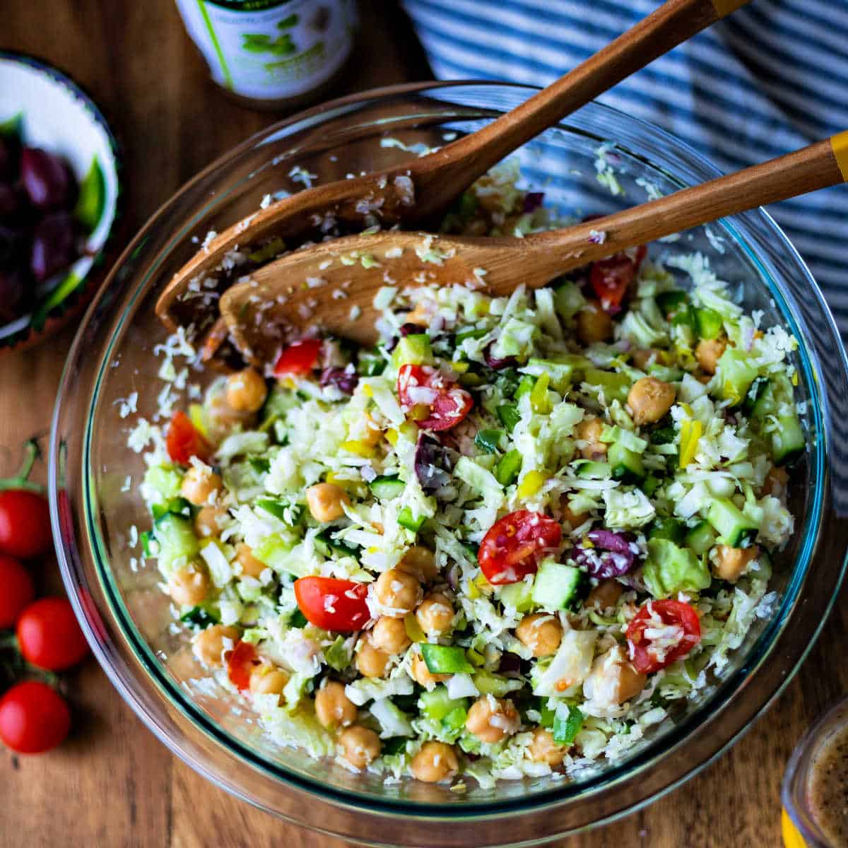 tossing healthy greek coleslaw with salad spoons