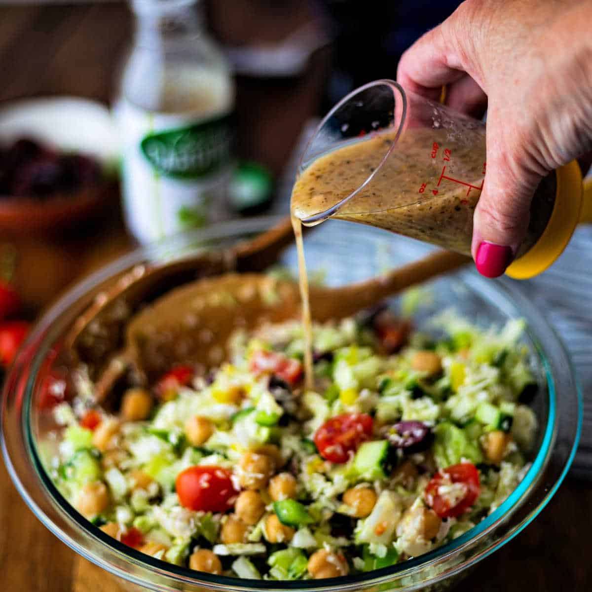 pouring dressing on healthy greek coleslaw 