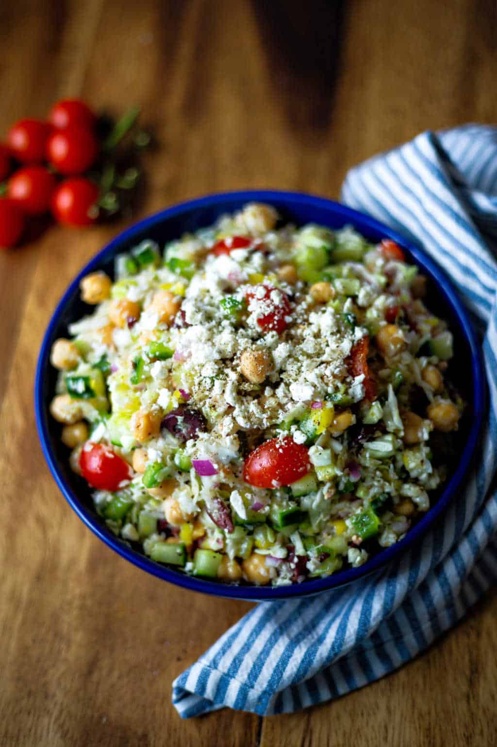 healthy greek coleslaw in a blue bowl garnished with feta cheese