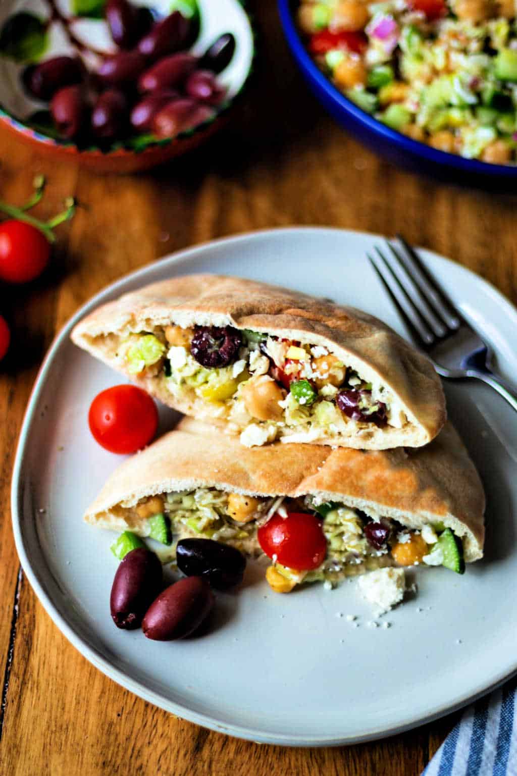 healthy greek coleslaw in pita pockets on a white plate with kalamata olives