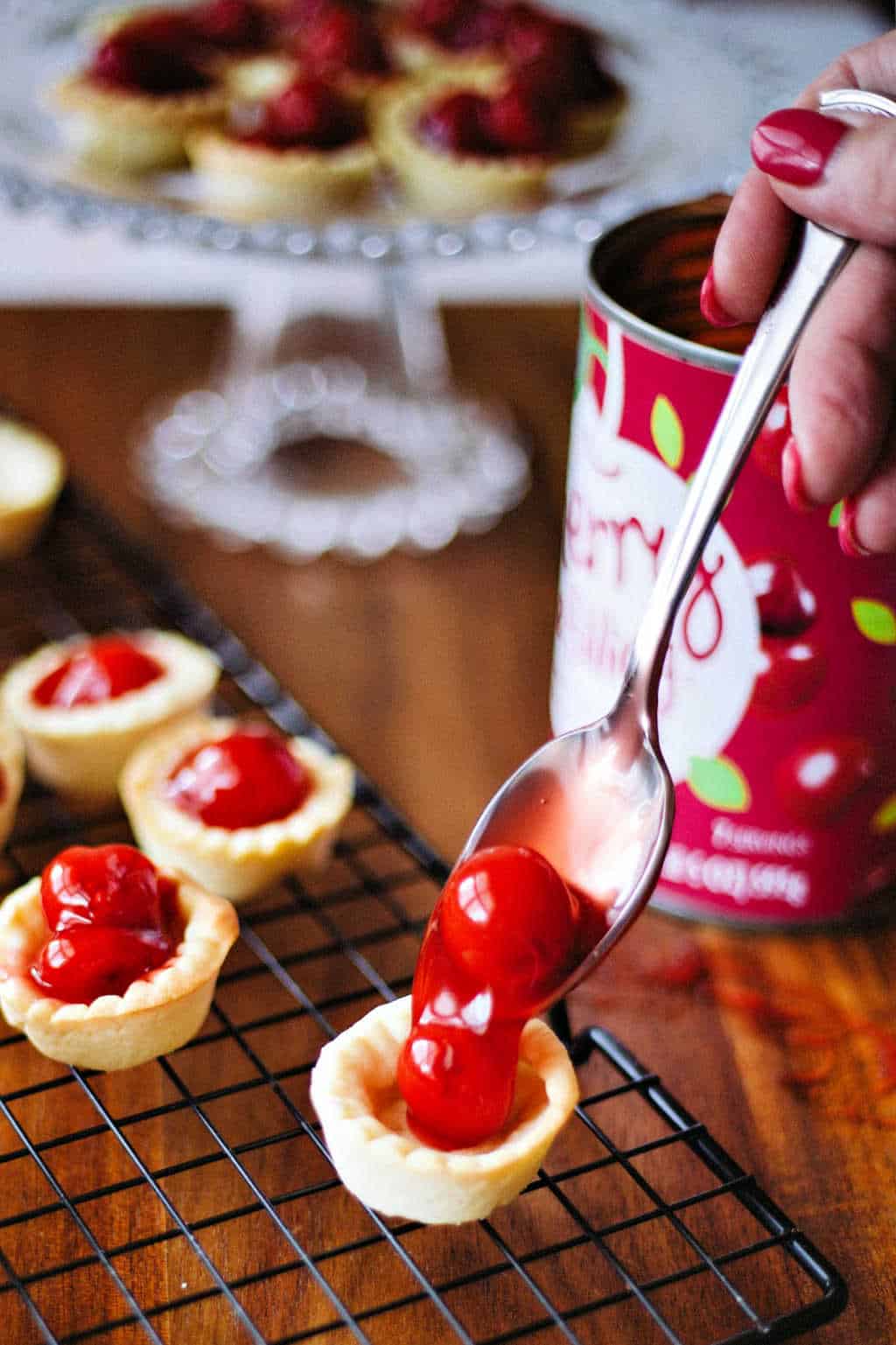 filling a miniature tart shell with canned cherry pie filling
