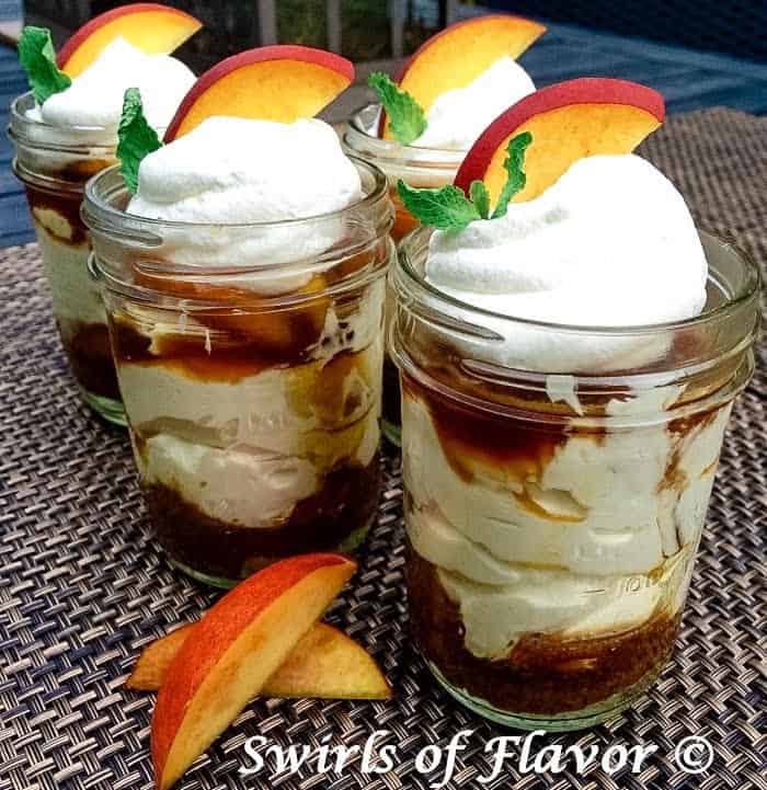 Bourbon Peach Cheesecake Mousse in mason jars garnished with peach slices.