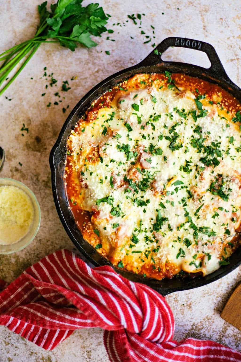 Skillet Lasagna with Squash and Mushrooms in a cast iron skillet with a red dish towel tied on the handle