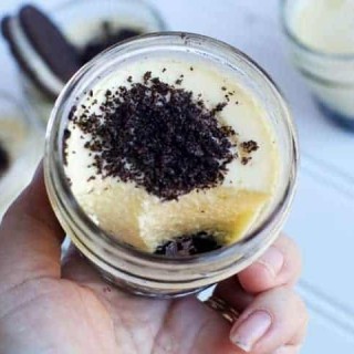 Chocolate Peanut Butter Cheesecake in a jar with cookie crumbles on top.