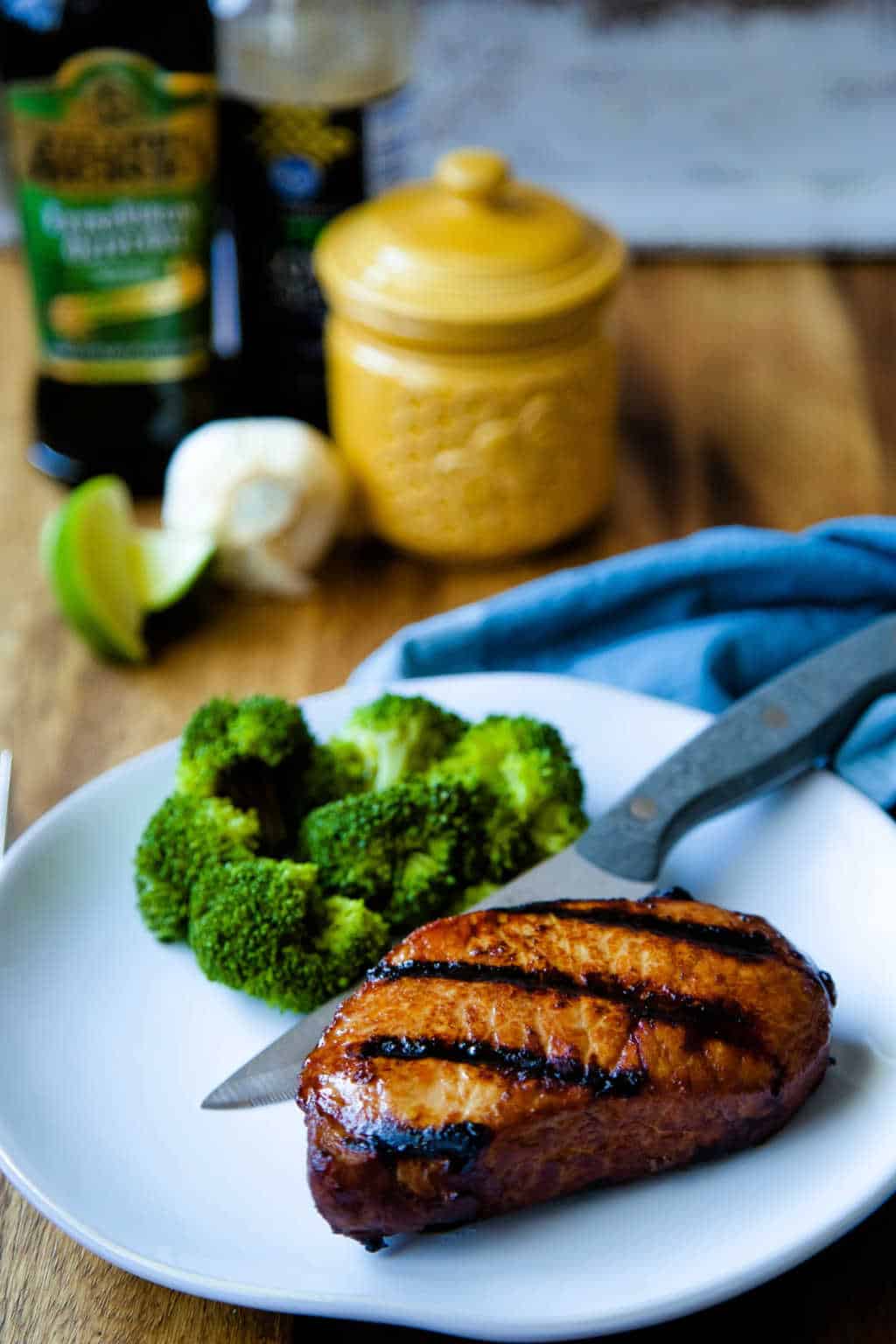 grilled pork chop on white plate with steak knife and broccoli