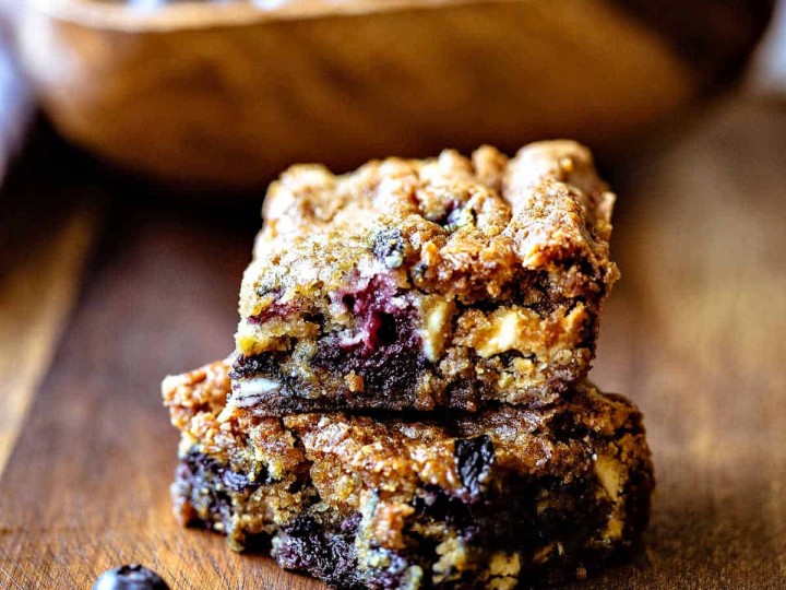 blueberry white chocolate chip cookie bars with a bowl of blueberries in the background