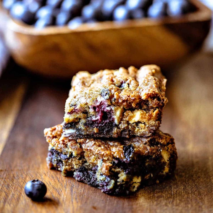 blueberry white chocolate chip cookie bars with a bowl of blueberries in the background