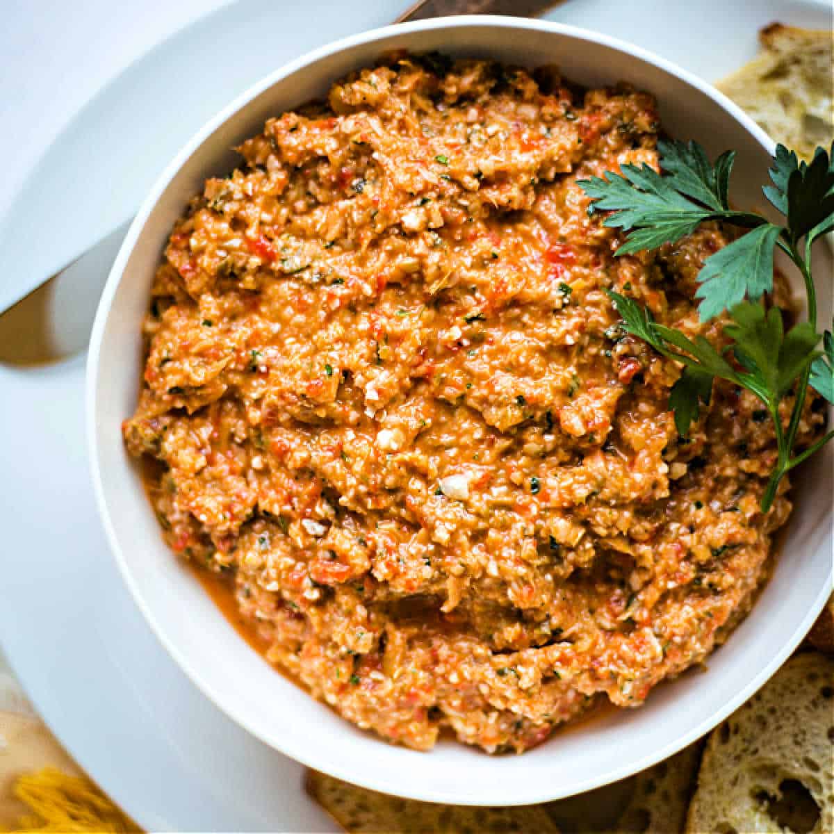 A bowl of red bell pepper tapenade on a plate