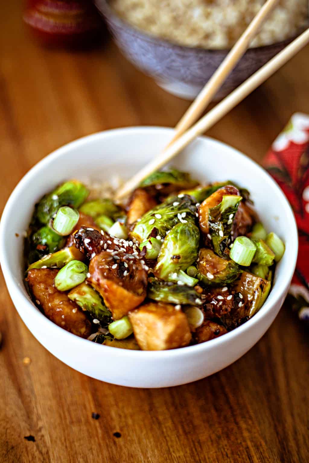 Sriracha Chicken and Brussels Sprouts Stir Fry in a white bowl with chopsticks