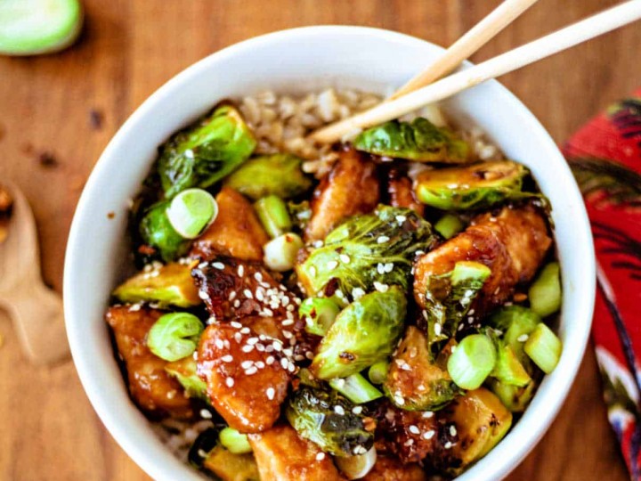 Sriracha Chicken and Brussels Sprouts Stir Fry in a white bowl with chopsticks