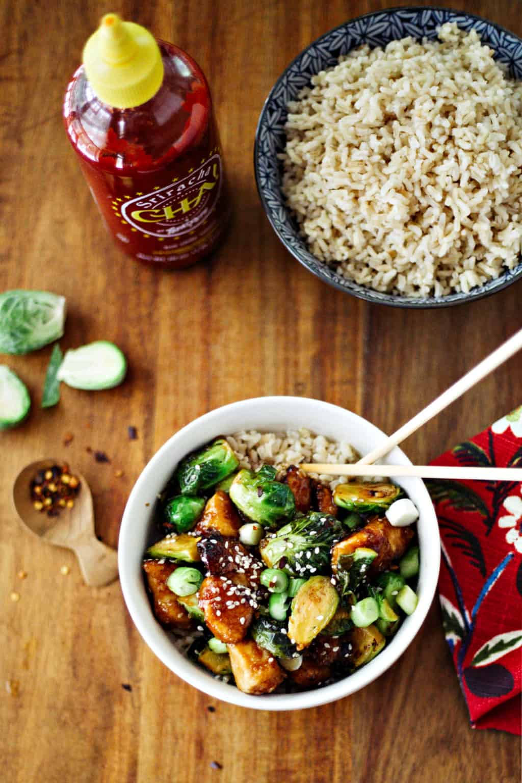 Sriracha Chicken and Brussels Sprouts Stir Fry in a white bowl with chopsticks and a bowl of rice