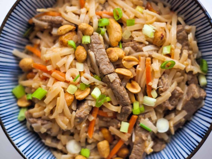 beef pad thai in a blue striped bowl