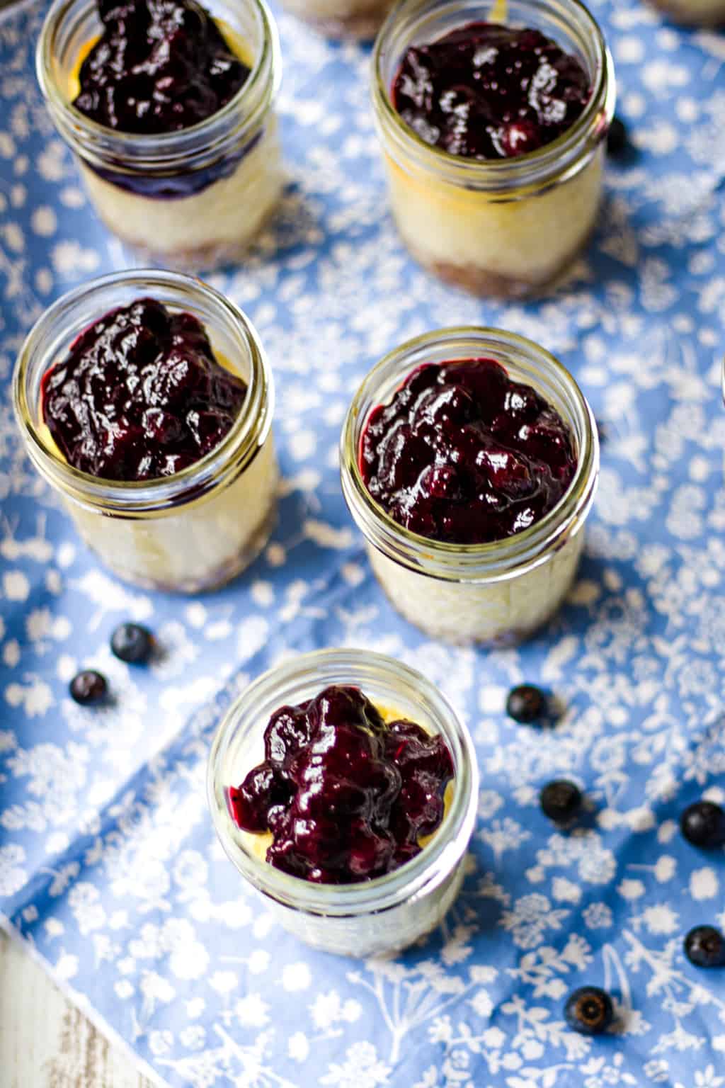 blueberry cheesecake in mason jars on a blue tablecloth