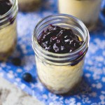 blueberry cheesecake in mason jars on a blue tablecloth